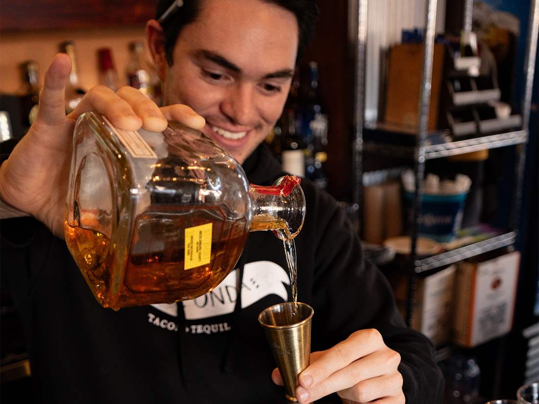 Que Onda team member pouring tequila